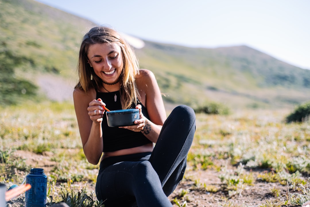woman-in-black-tank-top-and-black-pants-sitting-on-ground-holding-blue-ceramic-mug-during-bcfldsz-og8